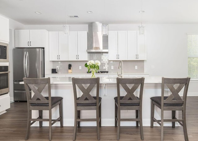 kitchen with wall chimney exhaust hood, visible vents, light countertops, a sink, and stainless steel appliances