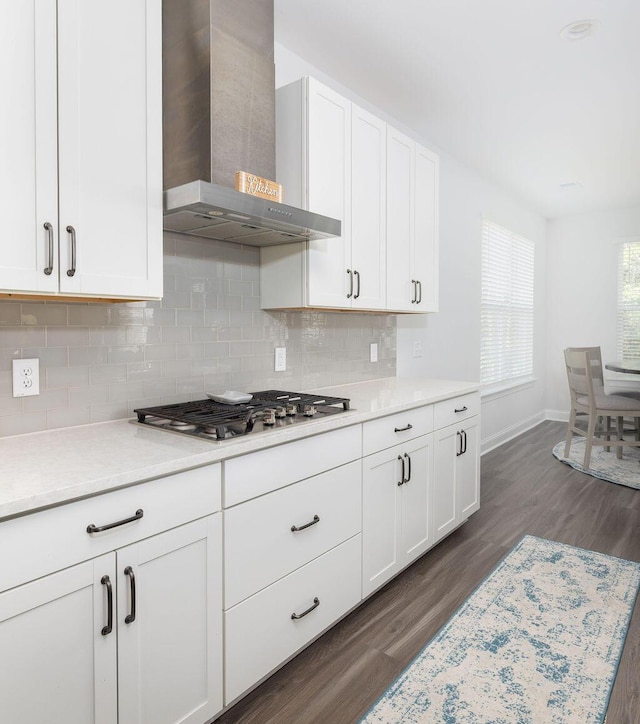 kitchen featuring stainless steel gas cooktop, light countertops, wall chimney exhaust hood, and dark wood-style floors