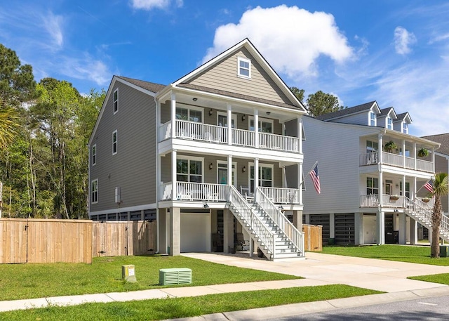 coastal home featuring a garage, covered porch, stairway, a front lawn, and concrete driveway