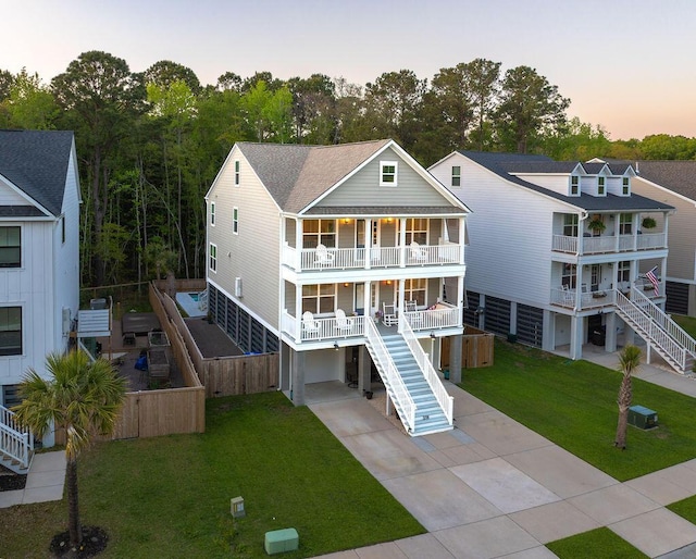 rear view of property featuring a carport, a yard, a porch, concrete driveway, and stairs