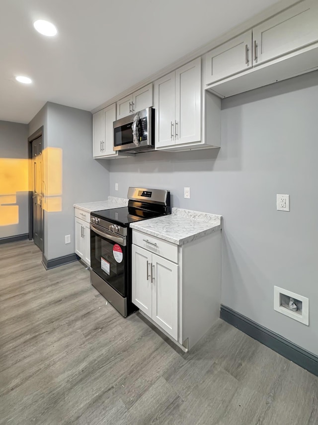 kitchen featuring stainless steel appliances, light stone counters, and light hardwood / wood-style floors