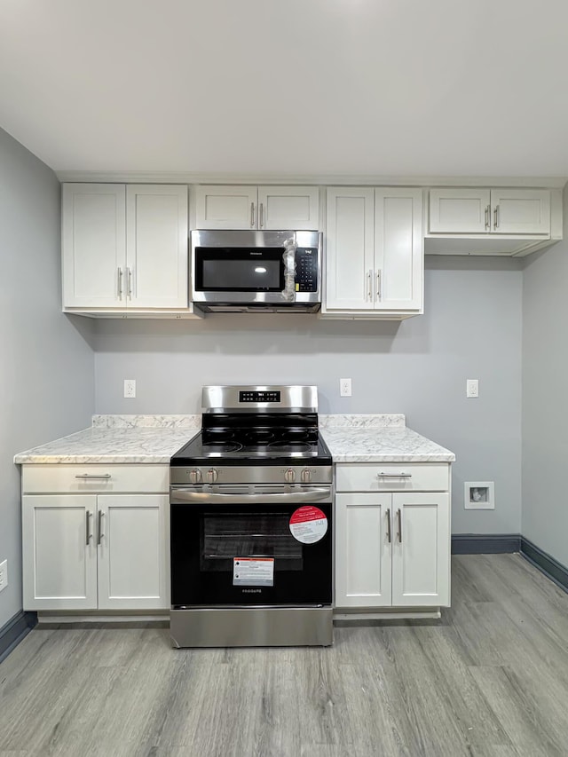 kitchen with light stone counters, stainless steel appliances, and light hardwood / wood-style floors