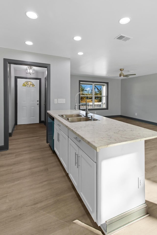 kitchen with sink, dishwasher, an island with sink, hardwood / wood-style floors, and white cabinets