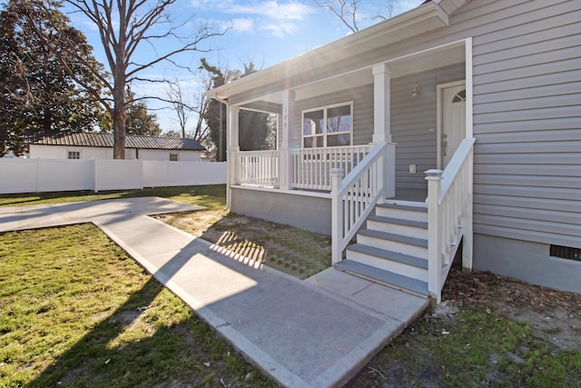 entrance to property featuring a porch and a lawn