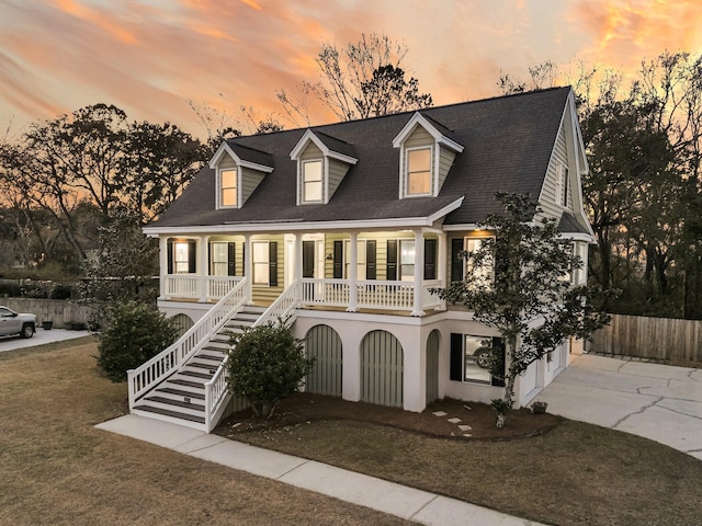 view of front facade featuring a porch, stairs, concrete driveway, stucco siding, and a front yard