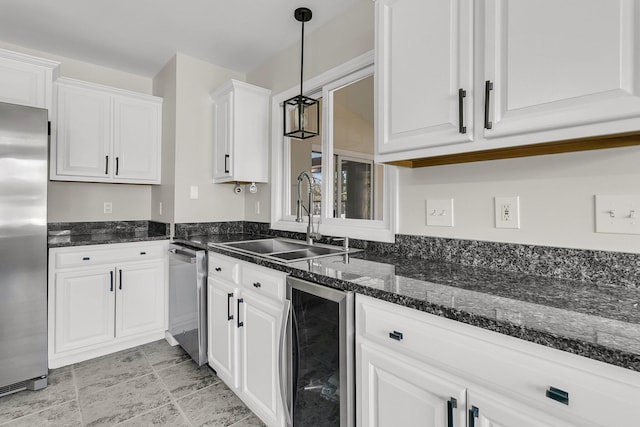 kitchen featuring wine cooler, a sink, white cabinets, stainless steel refrigerator, and decorative light fixtures