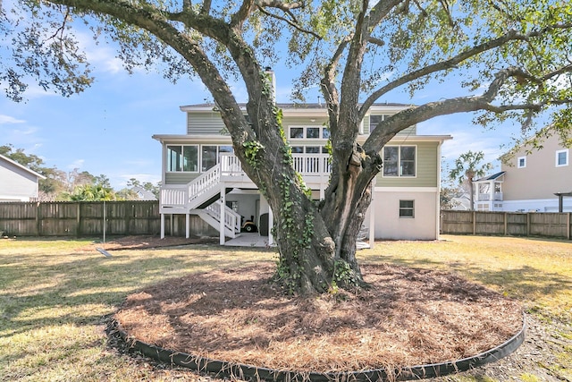 rear view of house featuring fence, a sunroom, stairs, a lawn, and a wooden deck