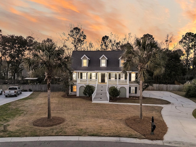 view of front of property with a yard, a porch, stairway, and fence