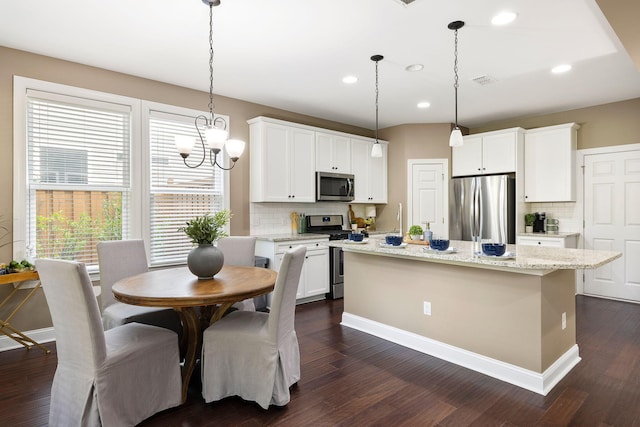 kitchen with hanging light fixtures, white cabinetry, appliances with stainless steel finishes, and a center island