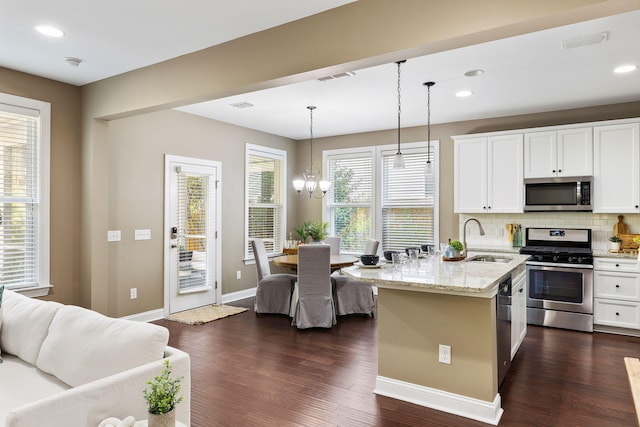 kitchen with pendant lighting, sink, appliances with stainless steel finishes, light stone counters, and white cabinets