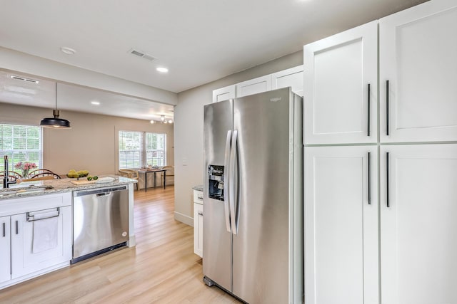 337 Price St, Goose Creek, SC 29445 - kitchen featuring stainless steel appliances, light wood finished floors, white cabinetry, a sink, and light stone counters
