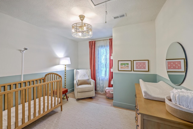 337 Price St, Goose Creek, SC 29445 - bedroom with wood finished floors, a textured ceiling, a nursery area, and attic access