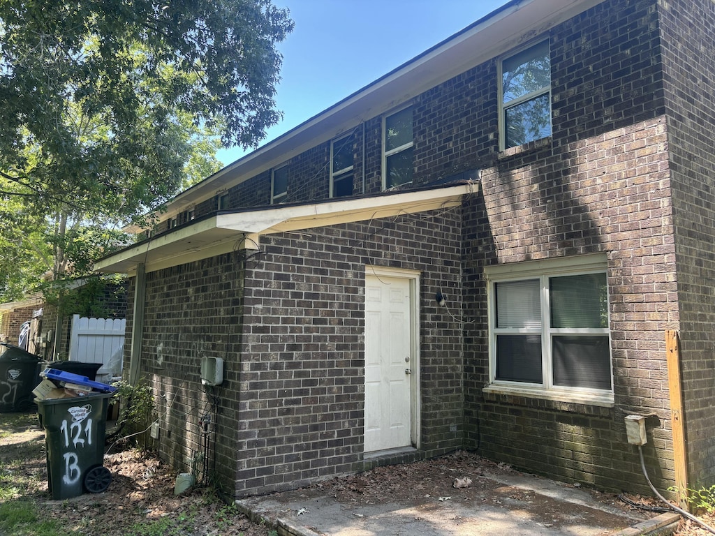 back of house with brick siding and fence