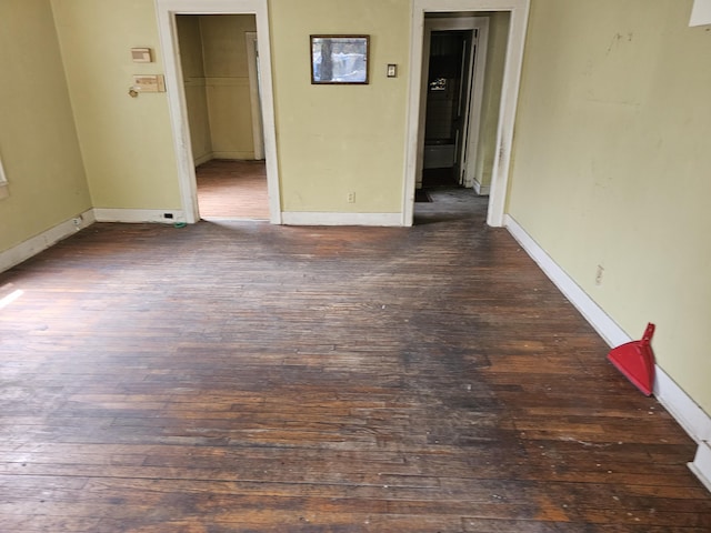 unfurnished room featuring baseboards and dark wood-style floors
