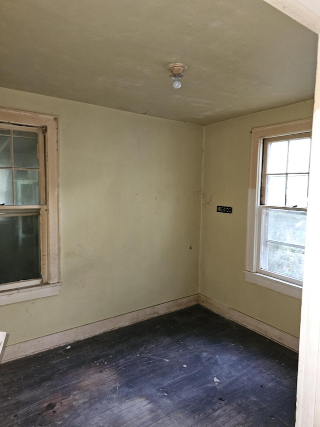 empty room featuring baseboards and dark wood-style flooring