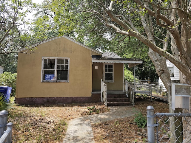 bungalow-style home featuring stucco siding, a shingled roof, and fence