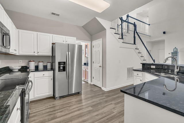 kitchen with sink, white cabinets, dark stone counters, hardwood / wood-style flooring, and stainless steel appliances