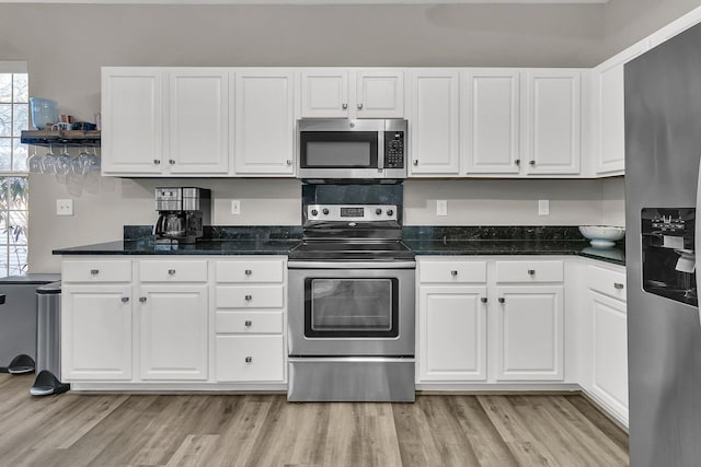 kitchen with appliances with stainless steel finishes, light hardwood / wood-style floors, and white cabinets