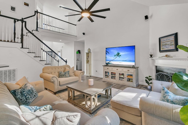 living room with a high ceiling, hardwood / wood-style floors, and ceiling fan