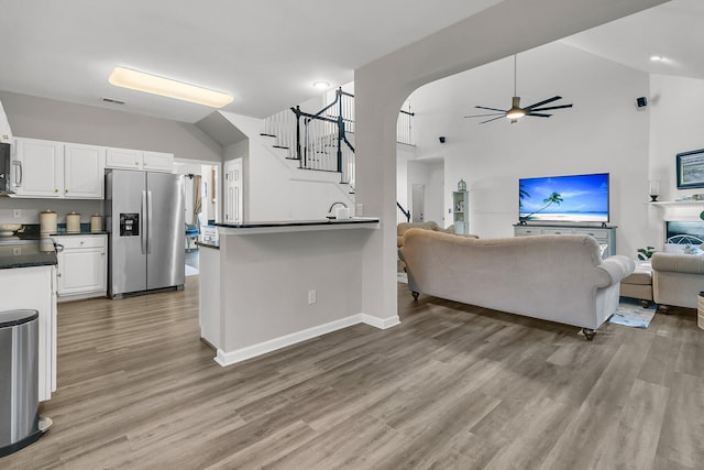 kitchen with stainless steel fridge, ceiling fan, light hardwood / wood-style floors, white cabinets, and kitchen peninsula