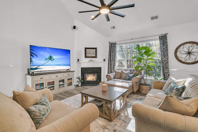 living room featuring ceiling fan, high vaulted ceiling, and light hardwood / wood-style flooring