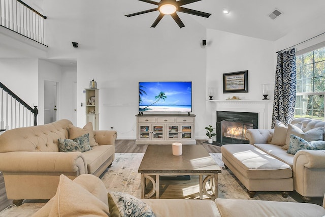 living room with ceiling fan, high vaulted ceiling, and light hardwood / wood-style floors