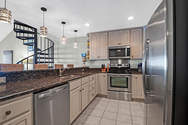 kitchen featuring hanging light fixtures, light tile patterned floors, sink, stainless steel appliances, and dark stone countertops