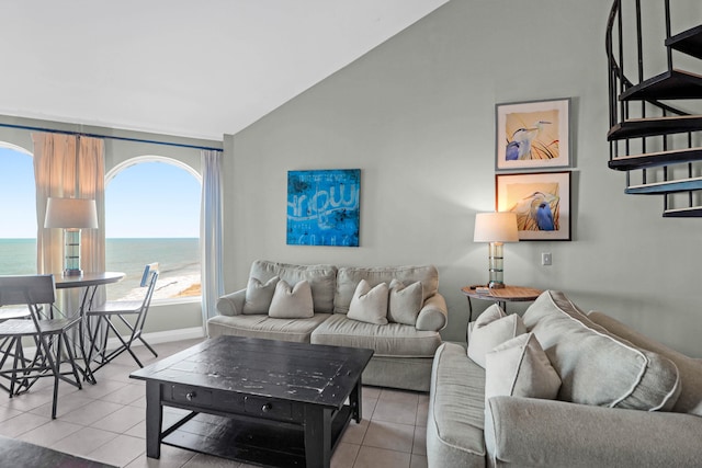 living room with lofted ceiling, a water view, and light tile patterned floors