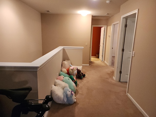 corridor featuring attic access, baseboards, light colored carpet, and an upstairs landing