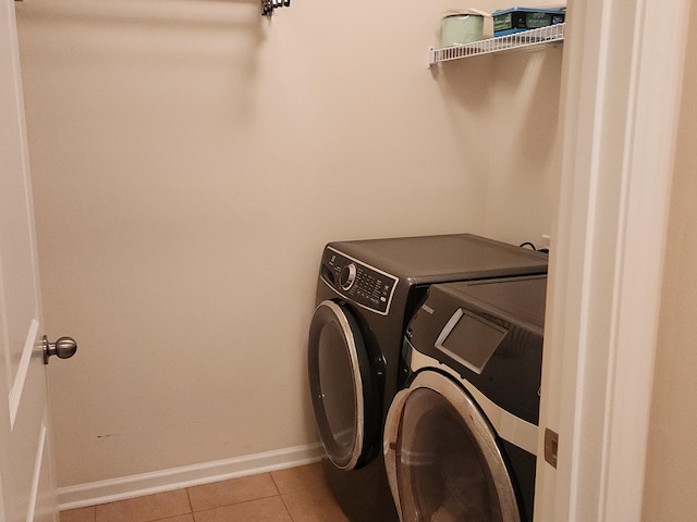 clothes washing area with laundry area, washing machine and dryer, baseboards, and tile patterned flooring