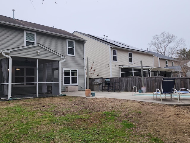 rear view of property with a sunroom, fence, a lawn, and a patio