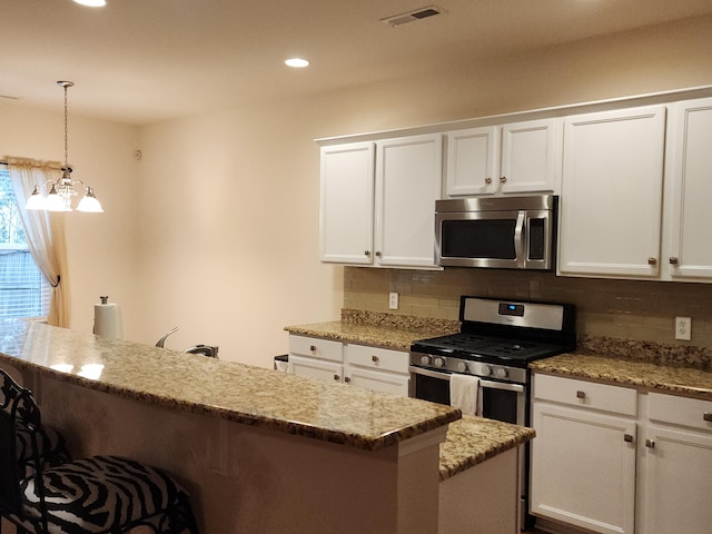 kitchen featuring appliances with stainless steel finishes, a kitchen bar, white cabinetry, and tasteful backsplash