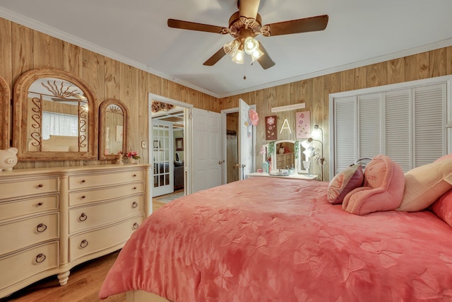 bedroom featuring a closet, ceiling fan, ornamental molding, and wood walls