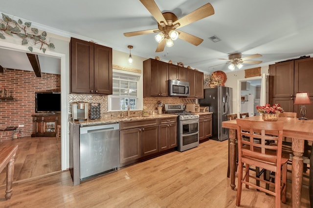 kitchen featuring sink, light wood-type flooring, tasteful backsplash, stainless steel appliances, and brick wall