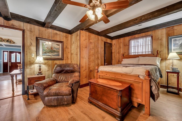 bedroom with beam ceiling, light hardwood / wood-style flooring, ceiling fan, and wooden walls