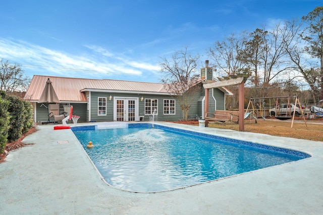 view of pool with a playground, a patio, and french doors