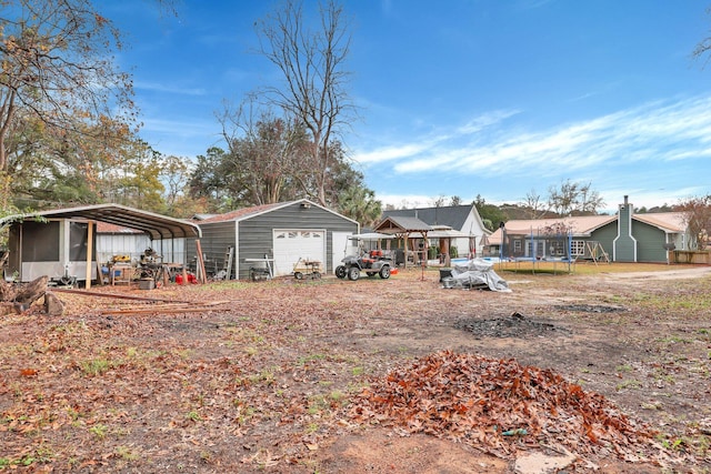 exterior space featuring a carport, a trampoline, a garage, and an outdoor structure