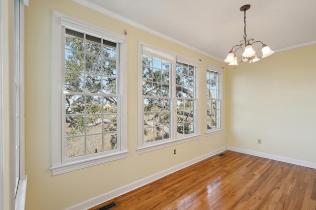 unfurnished dining area with light wood finished floors, visible vents, baseboards, ornamental molding, and a chandelier