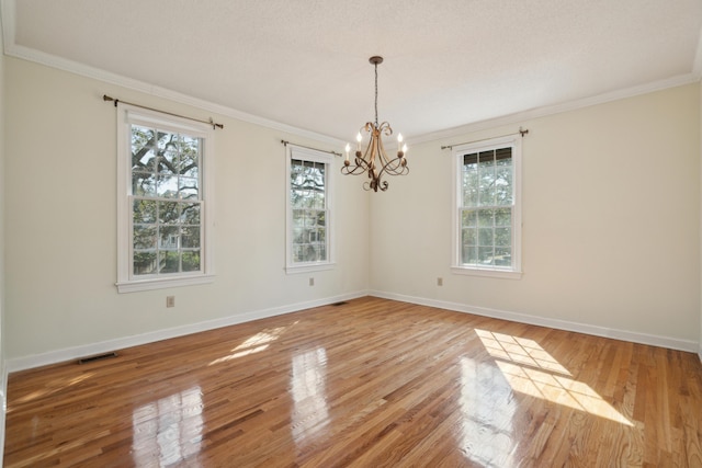 unfurnished room featuring light wood-style floors, visible vents, plenty of natural light, and ornamental molding