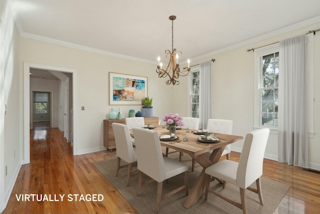 dining space featuring baseboards, visible vents, light wood-style flooring, crown molding, and a chandelier