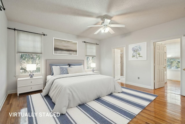 bedroom featuring ensuite bath, a textured ceiling, baseboards, and wood finished floors