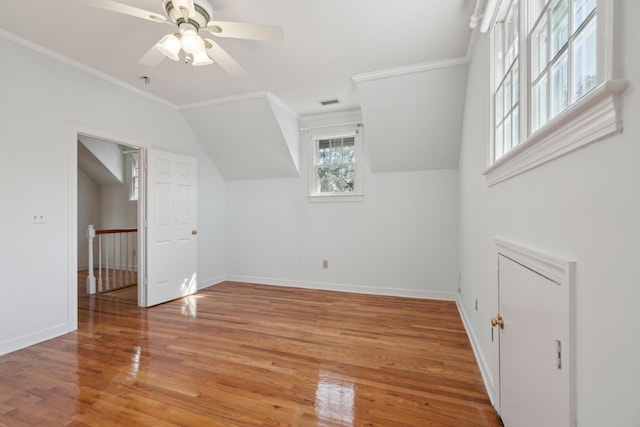 additional living space with lofted ceiling, visible vents, light wood-style floors, a ceiling fan, and baseboards