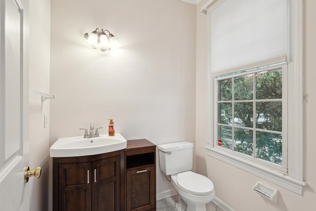 half bathroom featuring a wealth of natural light, baseboards, vanity, and toilet