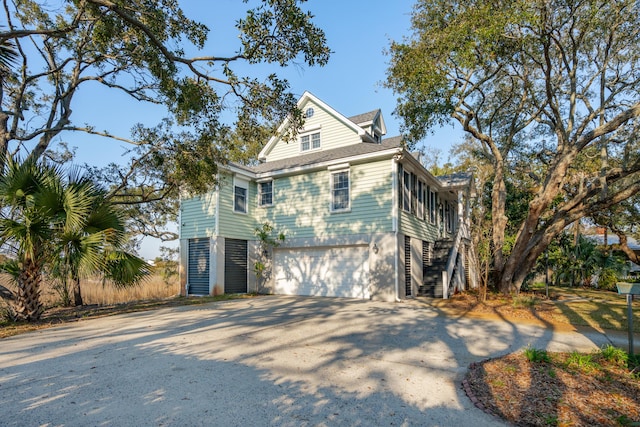 view of front of property with driveway, an attached garage, stairway, and roof with shingles