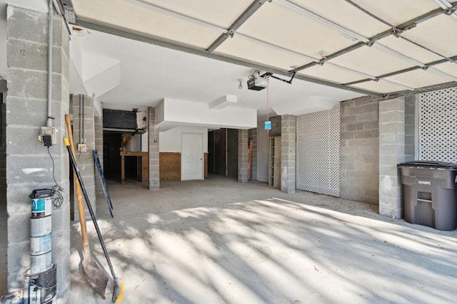 garage with a garage door opener and concrete block wall