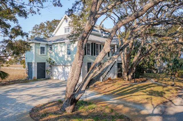 view of front facade featuring driveway, an attached garage, and stairway