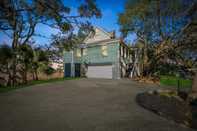 view of side of property with a garage, driveway, and stairway