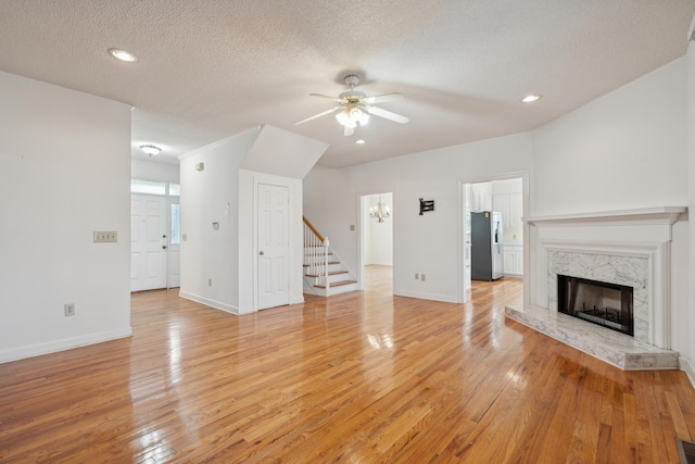 unfurnished living room featuring a high end fireplace, light wood-style flooring, and baseboards