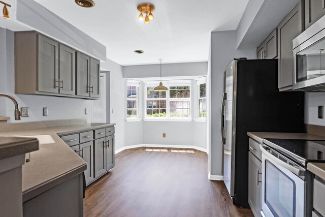 kitchen with sink, stainless steel appliances, pendant lighting, and dark hardwood / wood-style floors