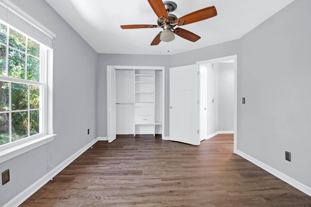 unfurnished bedroom with a closet, ceiling fan, multiple windows, and dark hardwood / wood-style floors